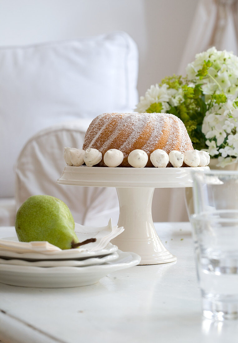Decorated bundt cake on cake stand and pear on plates