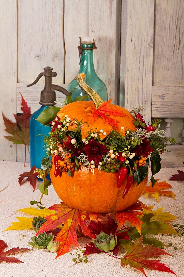Autumn arrangement of colourful leaves, pumpkin and garden flowers
