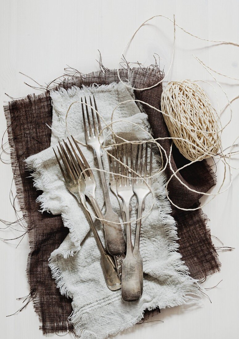 Old forks and kitchen twine on cloth