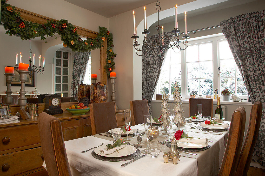 Landhaus-Esszimmer mit Weihnachtsgirlande an der Wand und festlich gedecktem Tisch