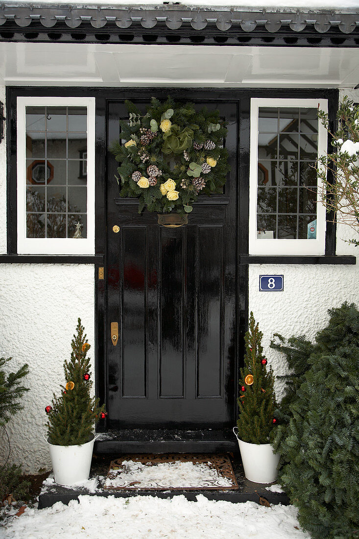 Eingangstür eines englischen Landhauses mit Adventskranz und Koniferentöpfen als weihnachtlicher Schmuck