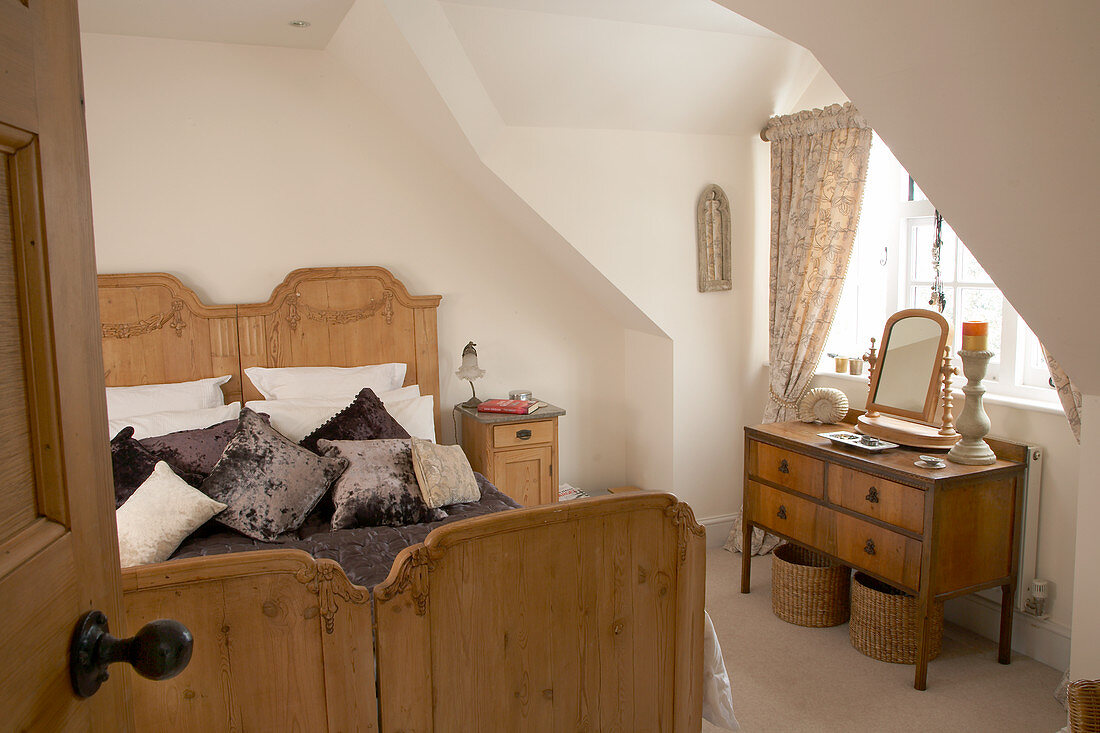 Antique twin beds and dressing table in front of dormer window in bedroom