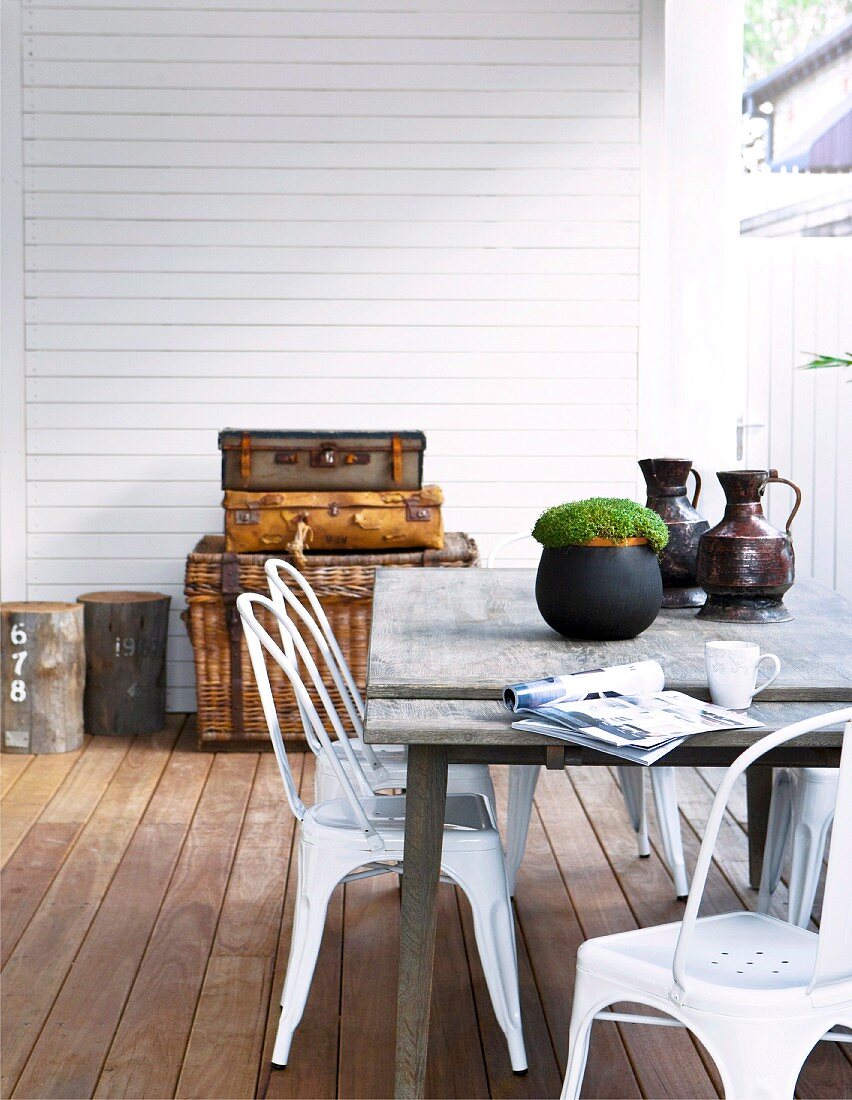 Metallstühle im Retrolook und schlichter Holztisch auf Terrasse mit Holzdielenboden