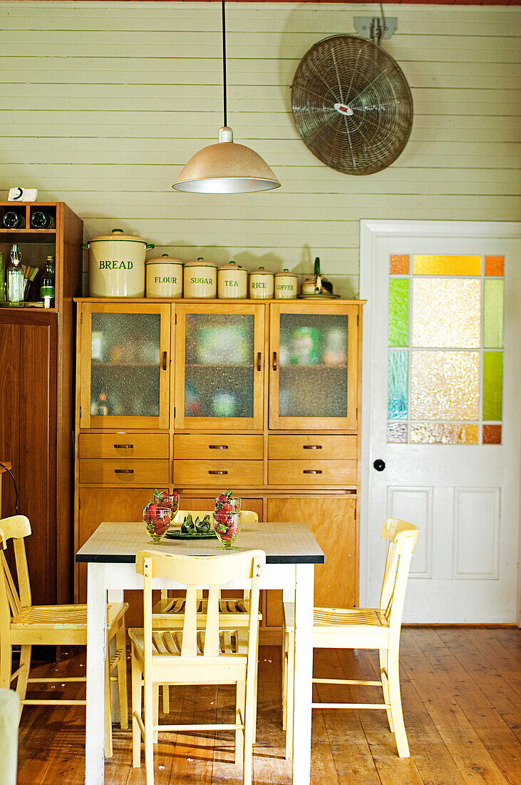 Simple country house kitchen with vintage furnishings and colourful glass inserts in panelled door