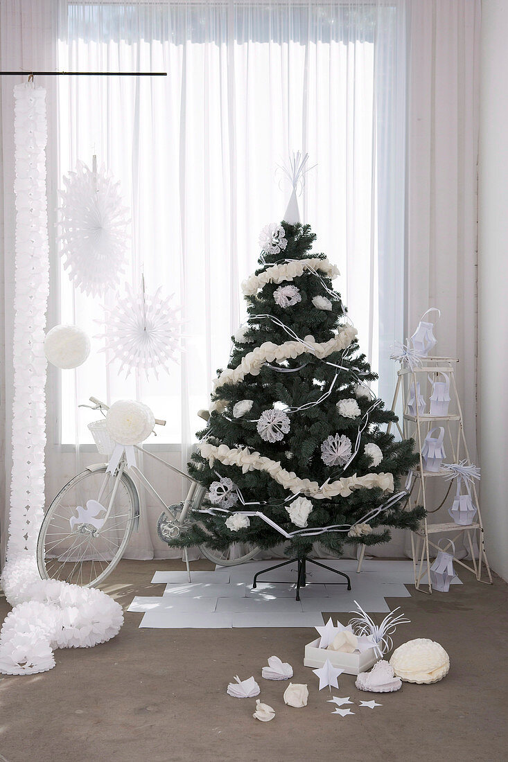 Geschmückter Weihnachtsbaum und Fahrrad als Geschenk am Fenster mit bodenlangem Vorhang