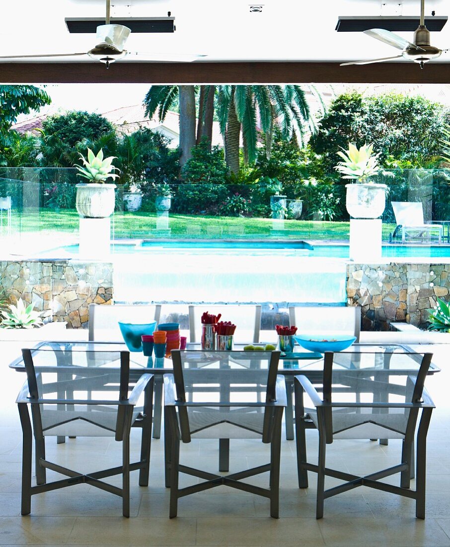Moderner Tisch mit Stühlen vor Pool in tropischem Garten
