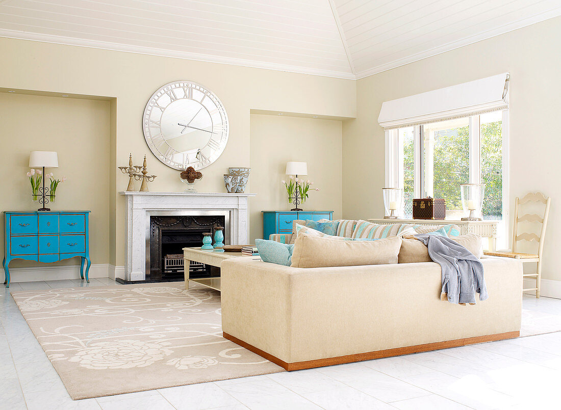 Pastellblaue, antike Zwillingskommoden neben offenem Kamin in traditionellem Wohnzimmer mit großer Couchlandschaft