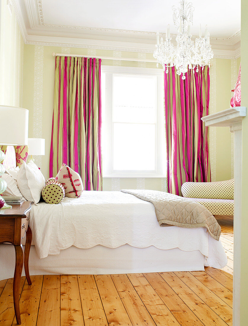 Fröhliche Fenstervorhänge in Pink und Braun in traditionellem Schlafzimmer mit Kristallleuchter und einfachem Holzdielenboden