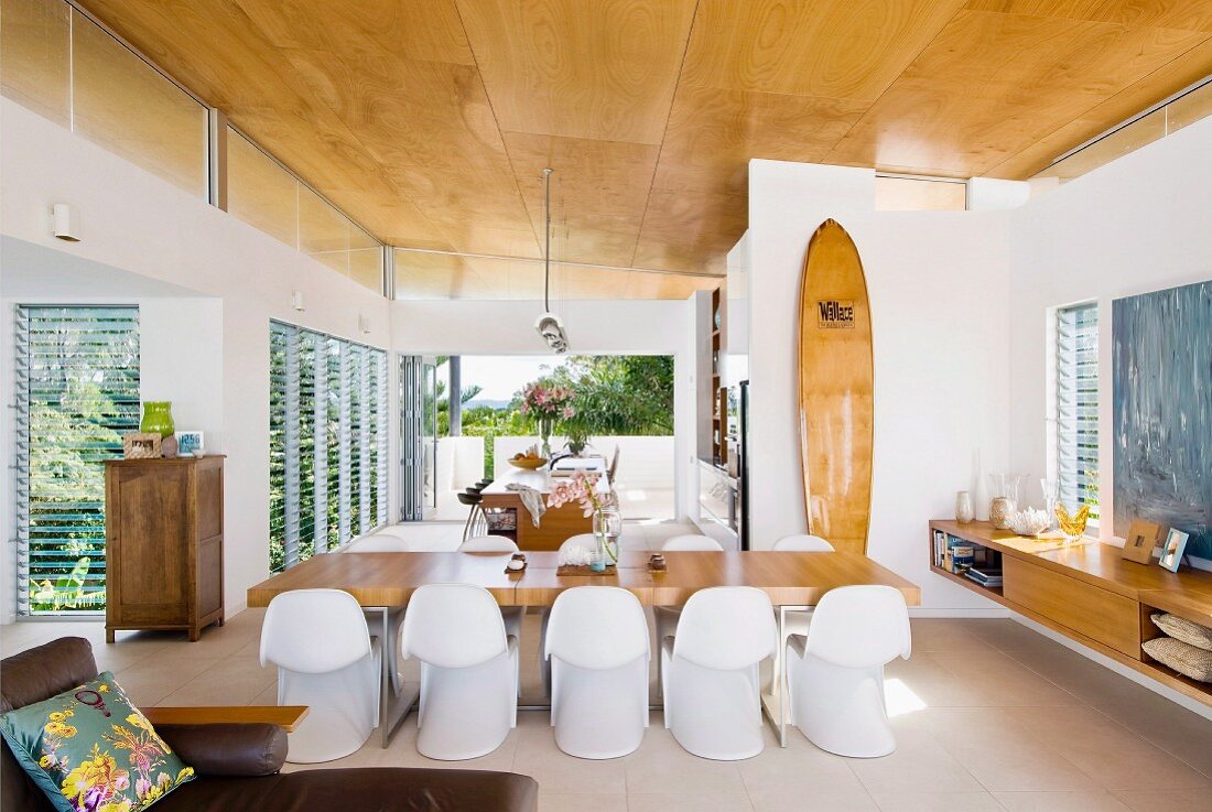 White, retro shell chairs at dining table in open-plan, contemporary interior