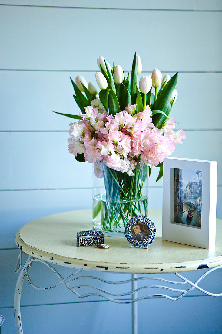 Bouquet of spring flowers on vintage metal table against blue wooden wall