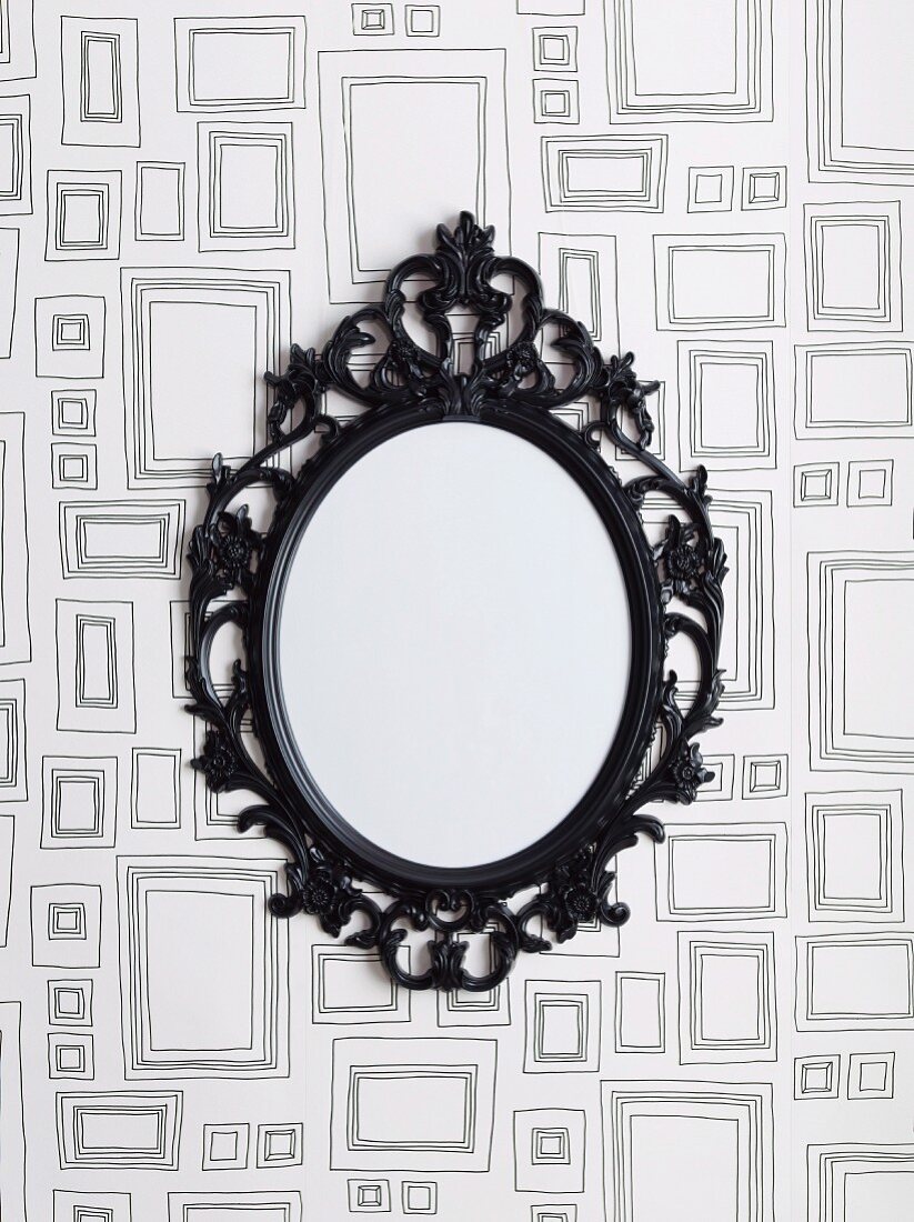 Mirror with black, vintage metal frame on patterned wallpaper