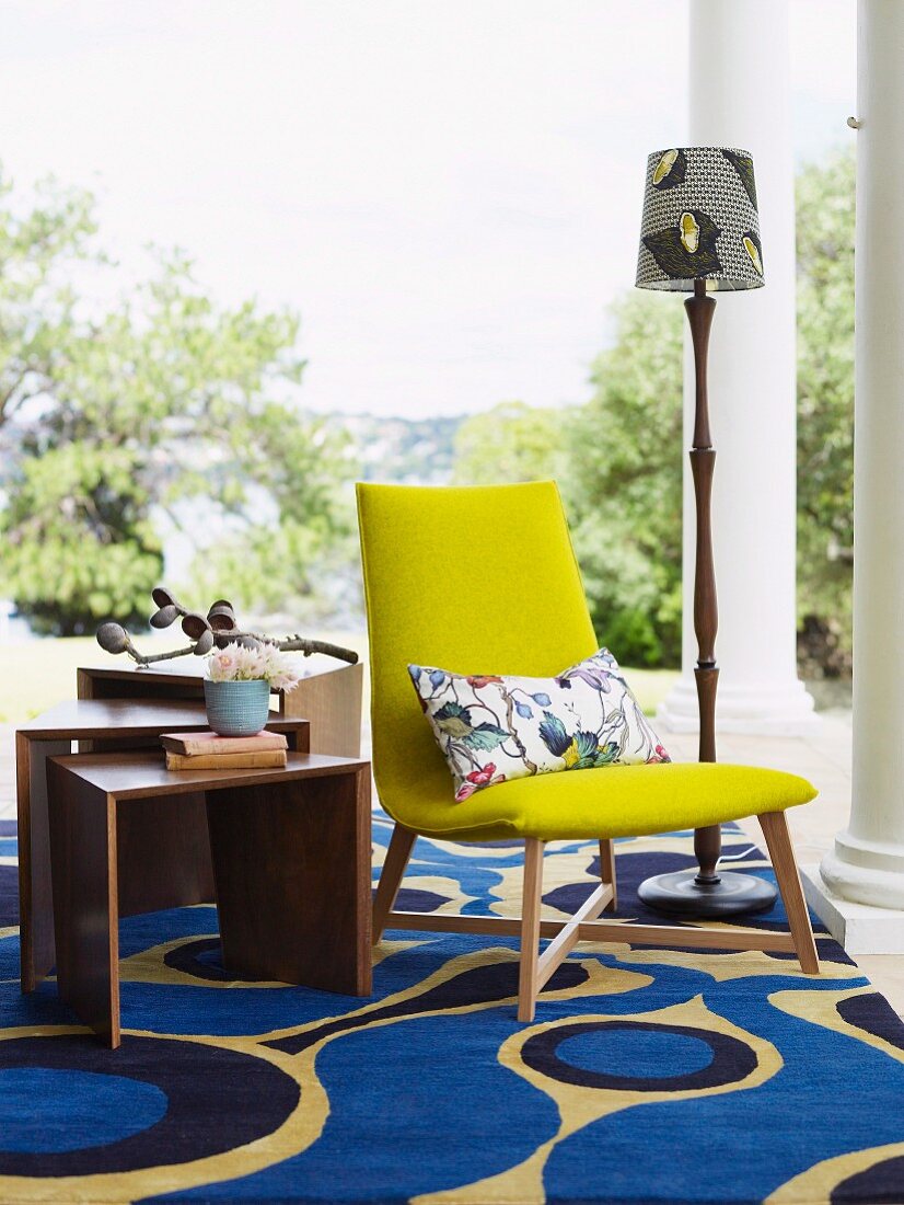 Gelber Polsterstuhl auf modernem Teppich mit klarem Muster auf Veranda mit dorischen Säulen