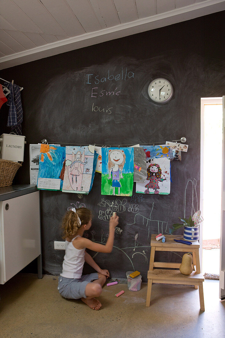 Girl drawing on blackboard wall in utility room