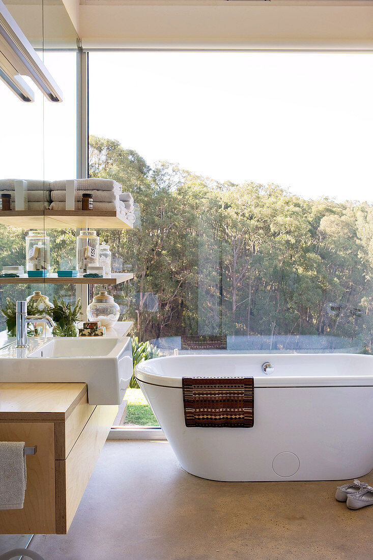 Designer-Badezimmer mit frei stehender Badewanne und Blick auf die Landschaft durch Glaswand
