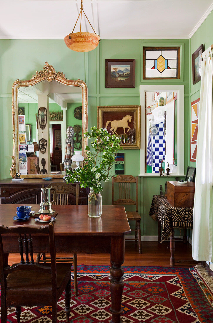 Dark wood dining table and chairs in Art Nouveau living room with green-painted walls