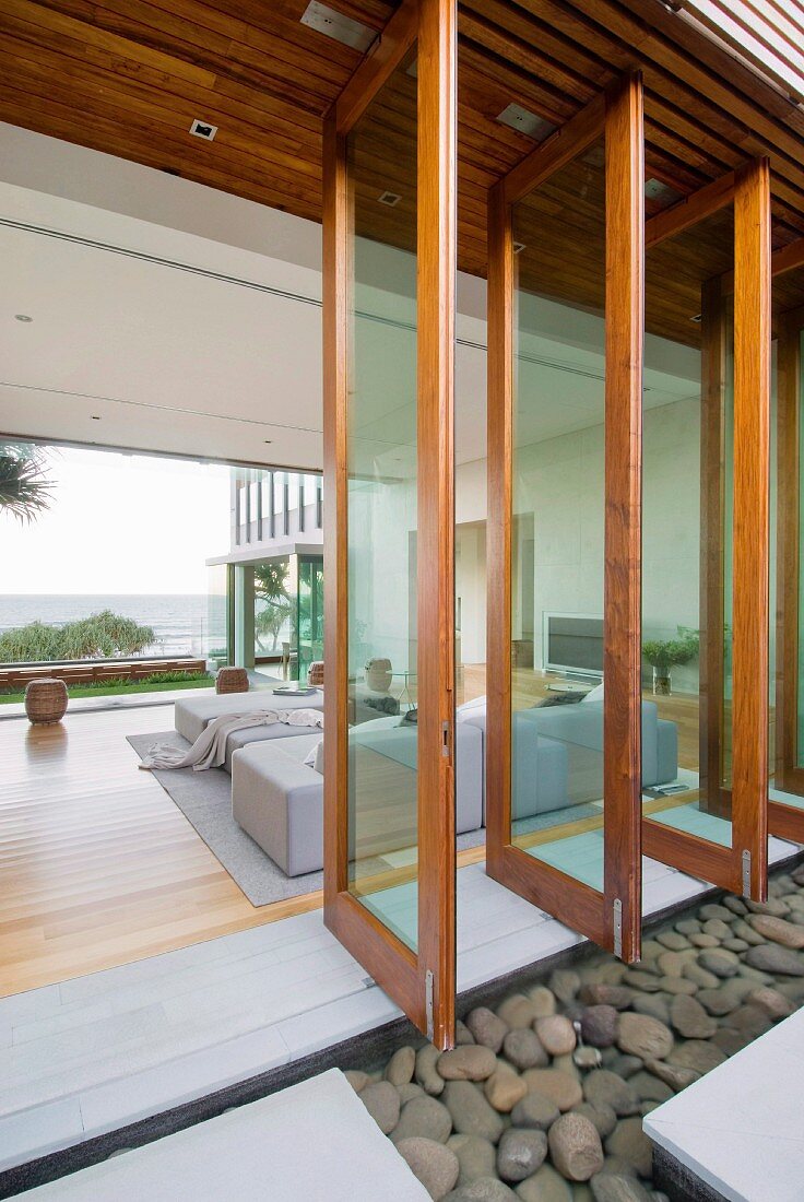 Blick durch geöffnete Drehfensterfront in modernen Wohnbereich mit Panoramablick