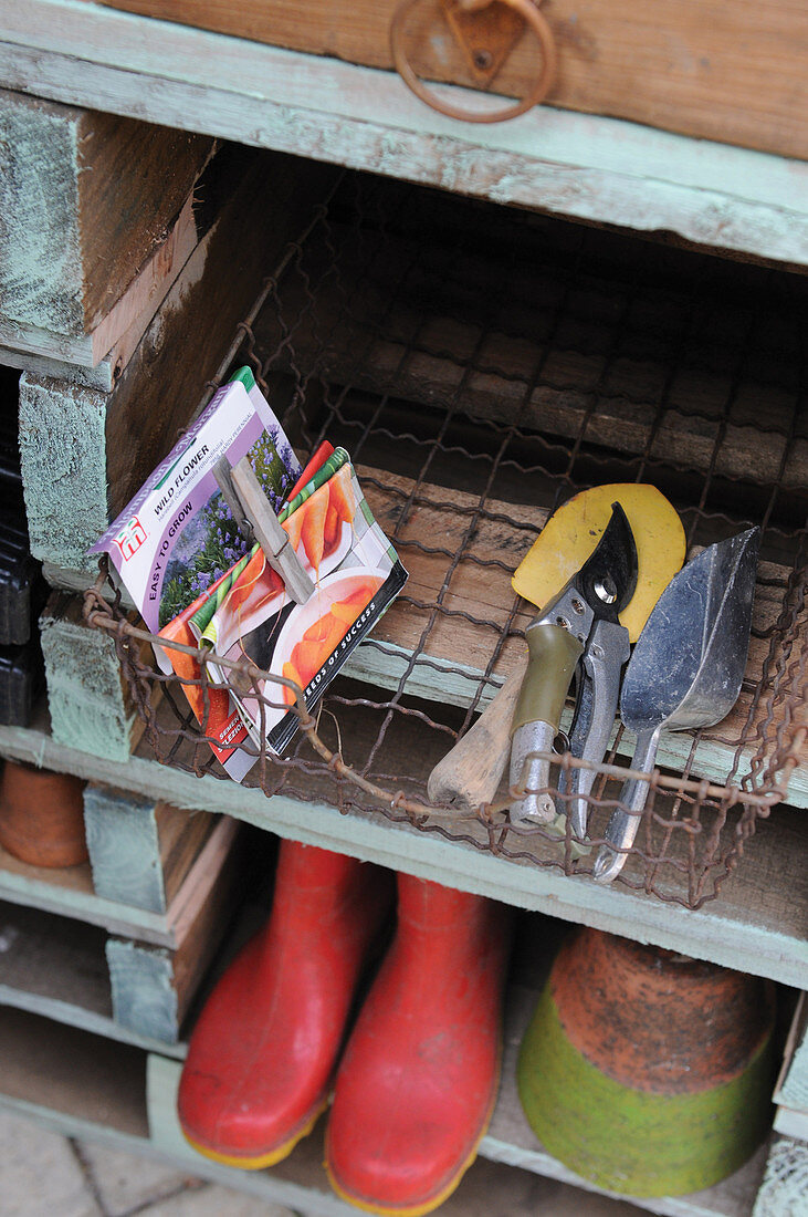 Gardening tools and shoes on wooden shelving
