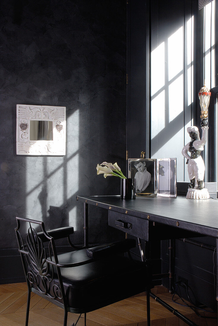 Desk below sunny window in corner of room with postmodern decor and anthracite walls
