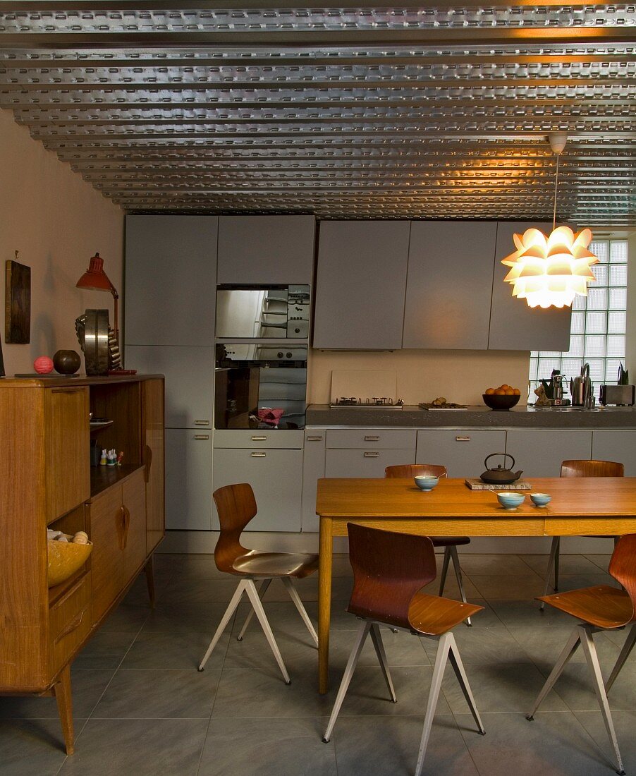 Moderne Stühle im Retrolook und schlichter Holztisch in offener Küche mit fünfziger Jahre Charme