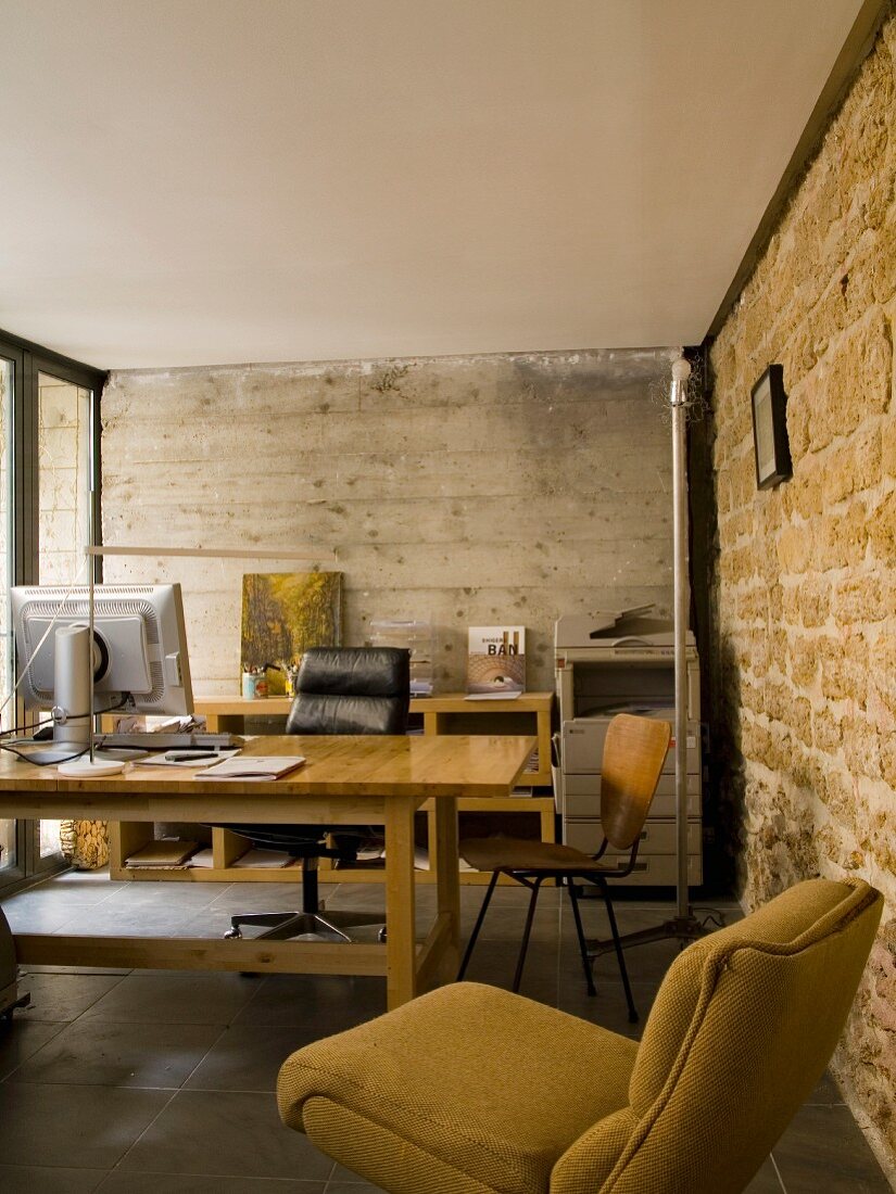 Rustic office with exposed concrete wall and stone wall - vintage-style seating around simple desk