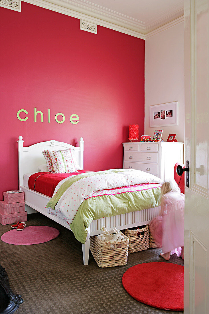 Kinderzimmer mit weißem traditionellem Bett vor roter Wand mit Stuckfries