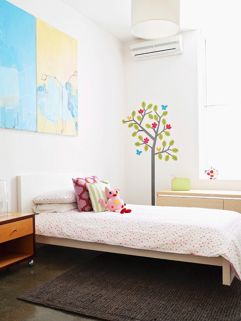 Bright, spartan child's bedroom with cheerful mural next to window