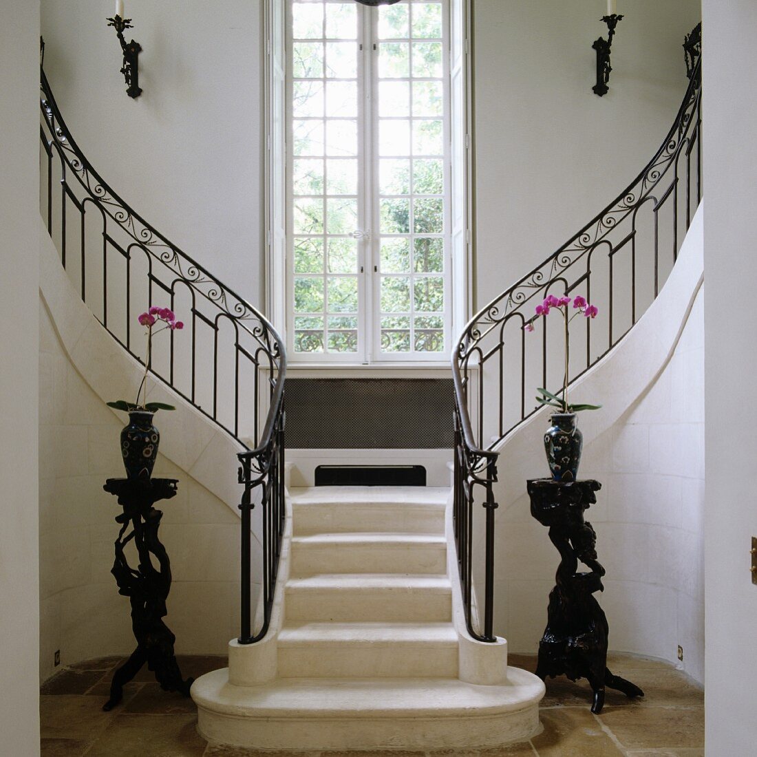 Vorraum eines mediterranen Landhauses mit zentralem Treppenaufgang, teilt sich in zwei Treppenläufe