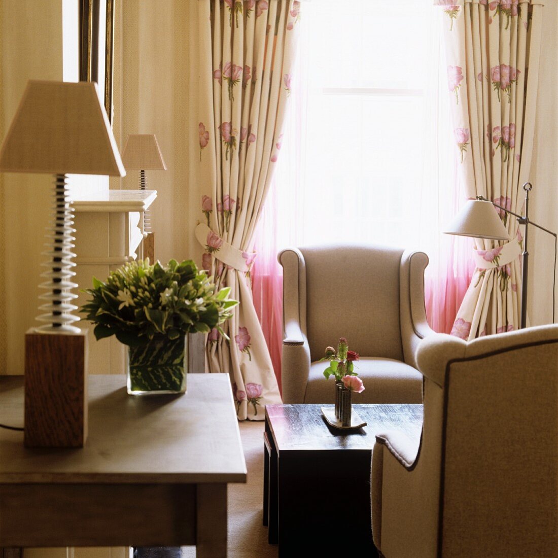 Tischlampe auf Tisch neben Loungeecke - Elegante Sessel und Kaffeetisch vor Fenster mit gerafften Vorhängen