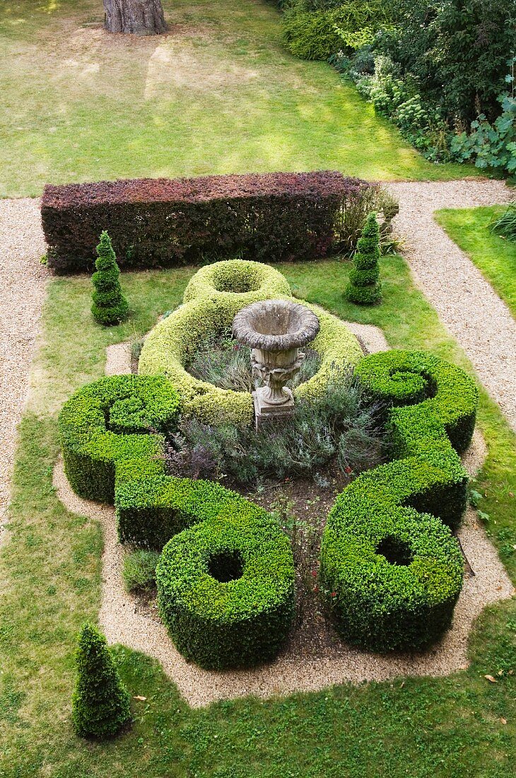 Gartengestaltung im Stil eines Schlossparks mit antiker Amphore inmitten kunstvoll geschnittener Buchsbaumhecken