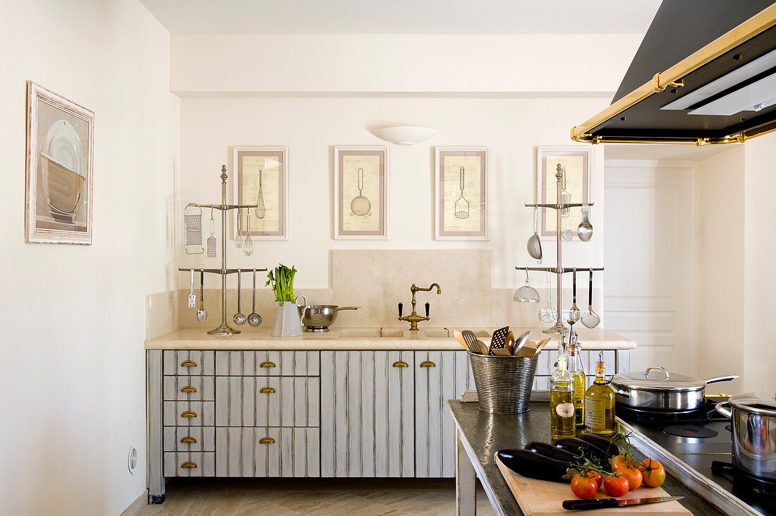 Landhaus-Retrostil in französischer Wohnküche mit Muschelgriffen aus Messing an hellgrau gestreiften Fronten
