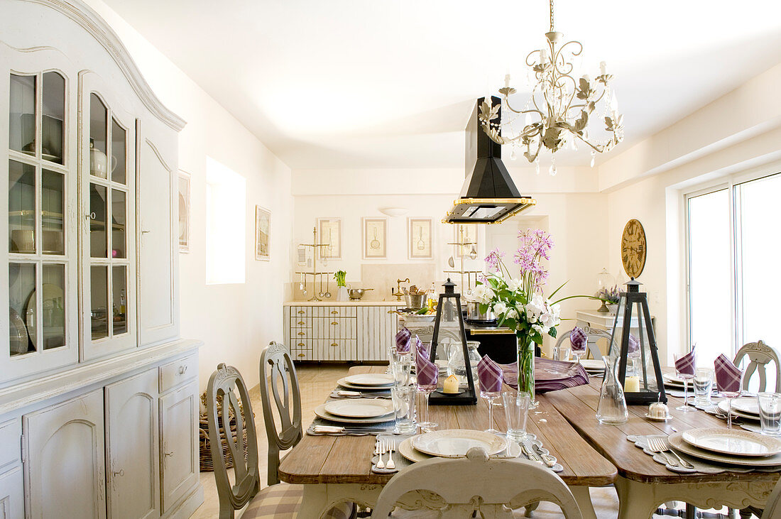 Festlich gedeckter Tisch in großer Wohnküche mit Essplatz und Geschirrschrank im französischen Vintagestil