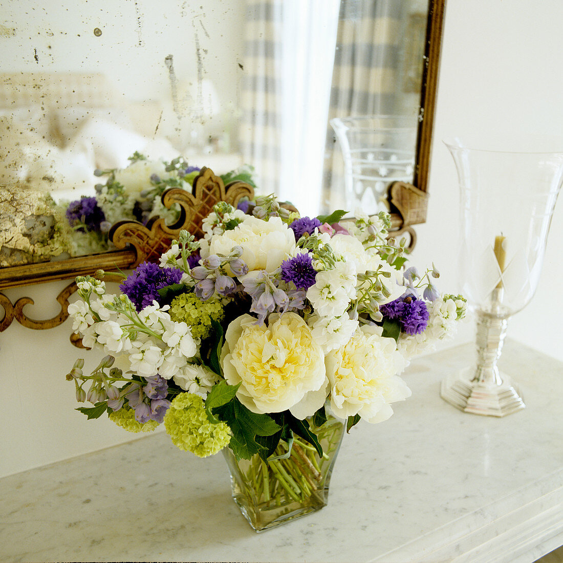 Bouquet on marble shelf in front of mirror with dull spots
