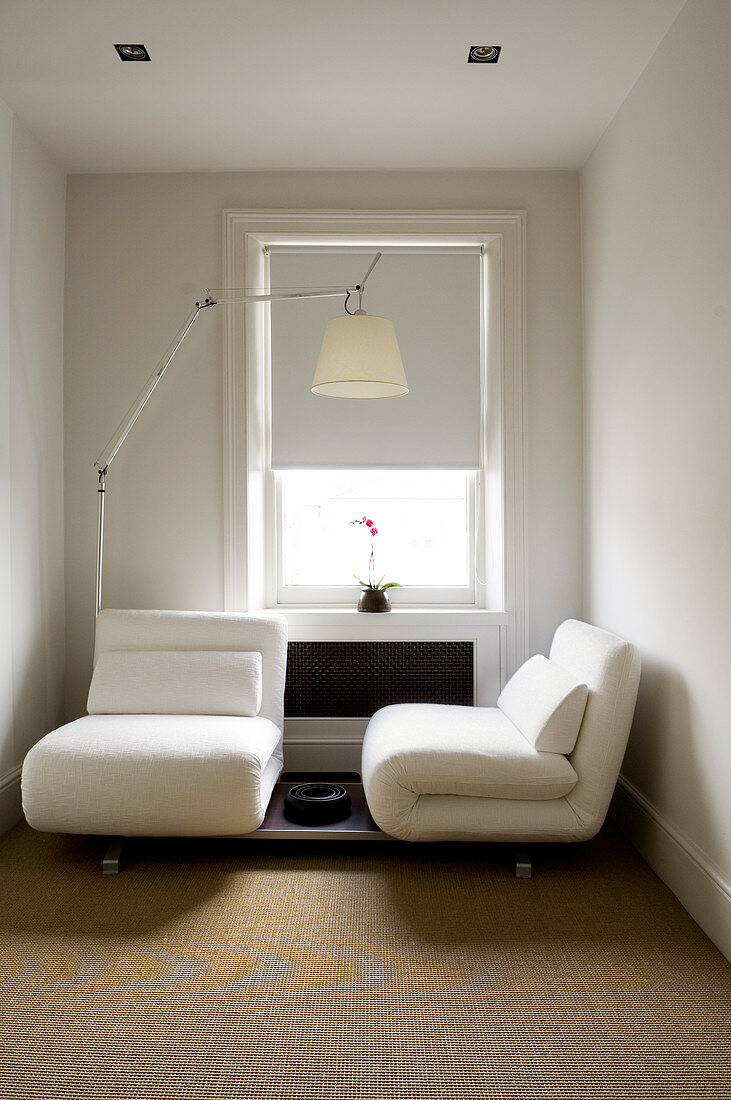 Kleines, feines Gästezimmer mit klappbaren Sessel-Elementen und Designerleuchte von Artemide
