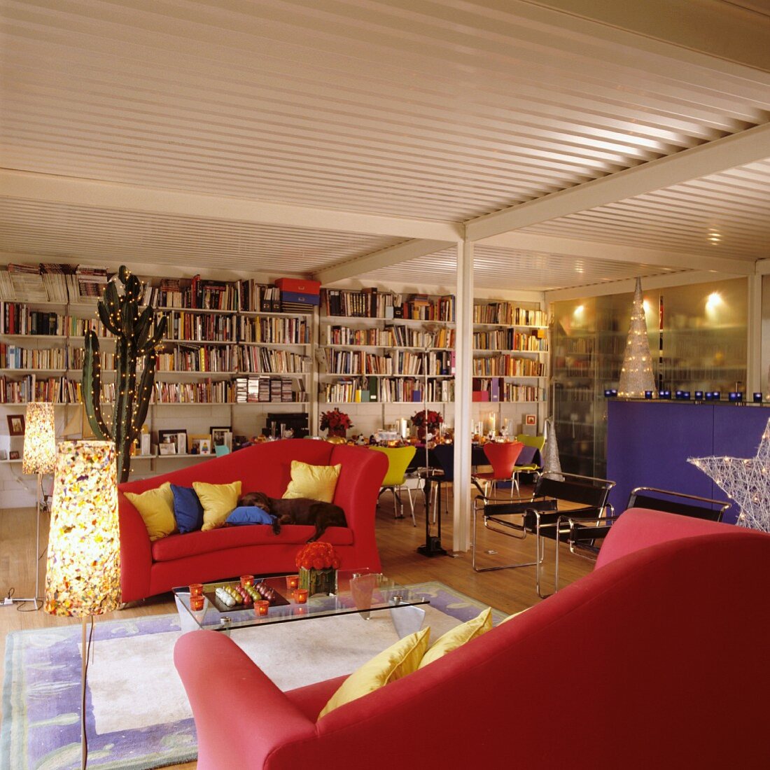 Rote Sofas und eine volle Bücherwand in weihnachtlich dekorierter Loftwohnung mit Trapezblechdecke