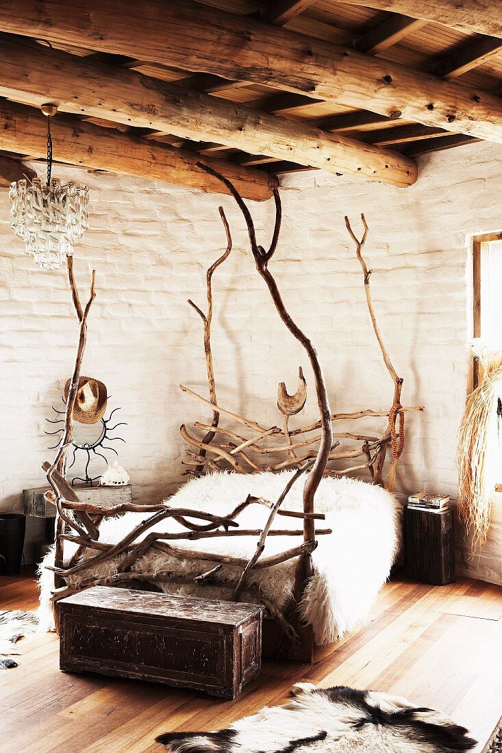 Selbstgebautes Bett aus Naturhölzern in rustikalem Schlafzimmer mit Holzbalkendecke