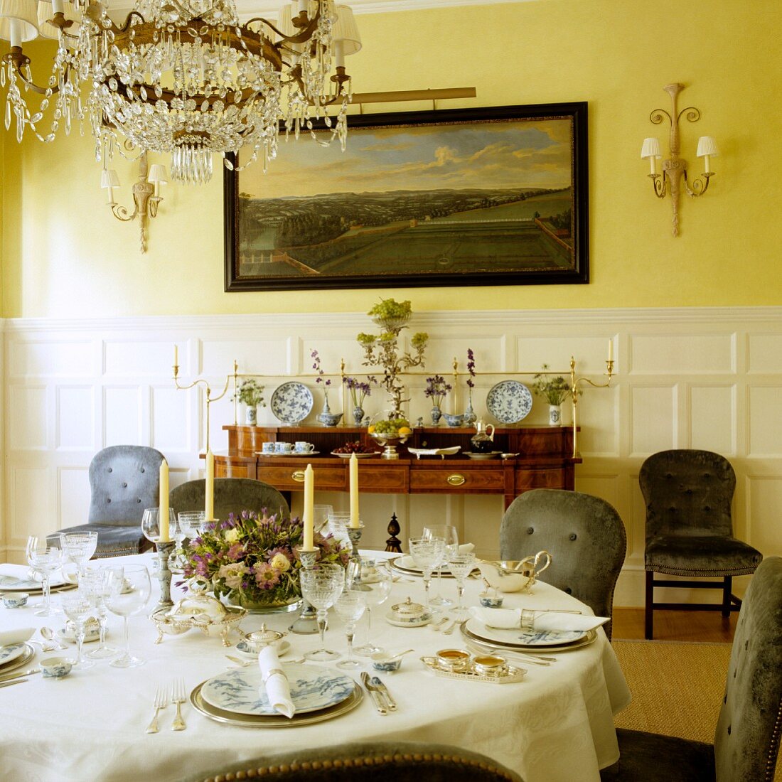 Festively set dinner table in grand dining room with yellow-painted walls and half-height, white wood panelling