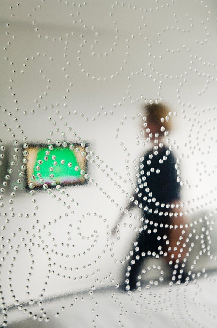 Pane of glass with floral pattern of dots and view of woman beyond