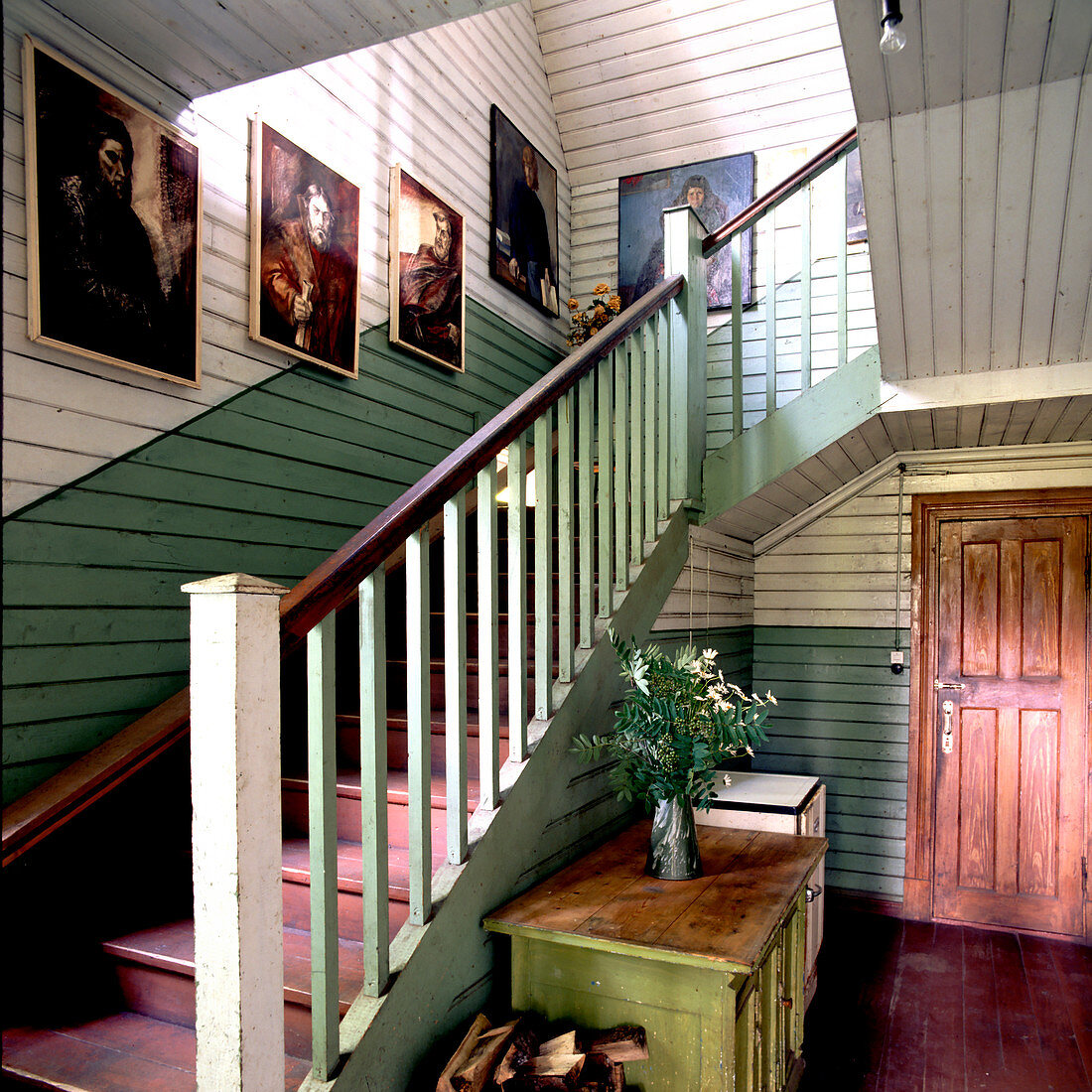 Ausgestellte Ölportraits in schlichtem Treppenhaus eines nordischen Holzhauses