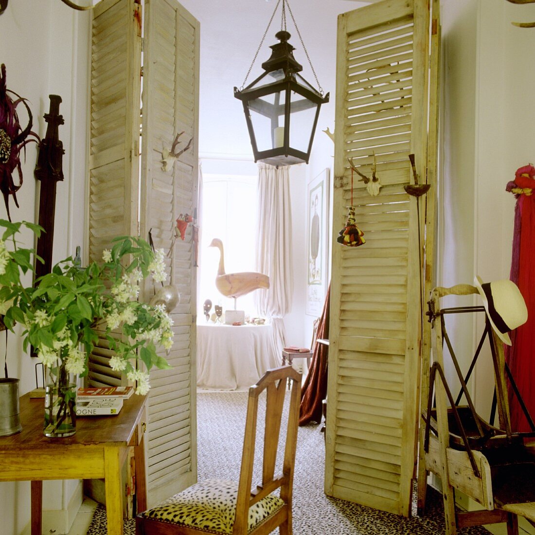 Vintage Raum mit offenen Falttüren und Blick auf laternenförmige Hängelampe und Tisch im Hintergrund