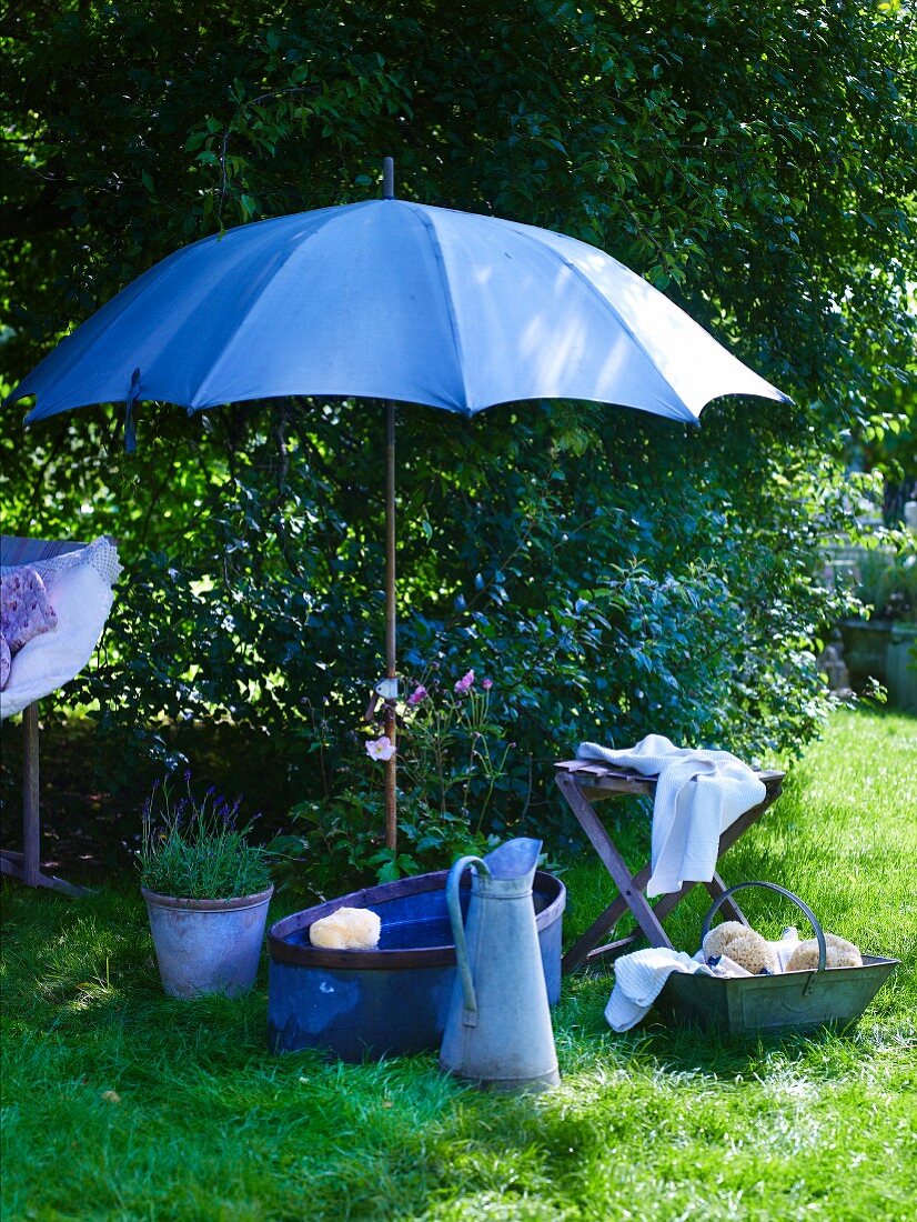 Vintage Waschutensilien unter aufgespanntem Sonnenschirm im Garten