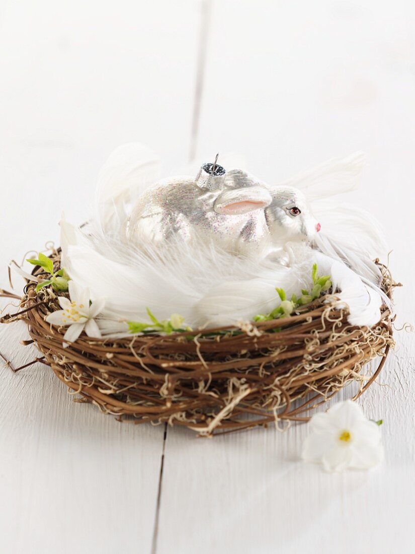 A silver rabbit in a nest of feathers and twigs