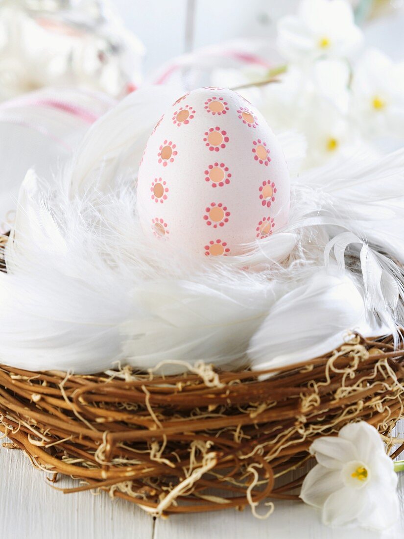 Decorated Easter egg in nest of feathers & twigs