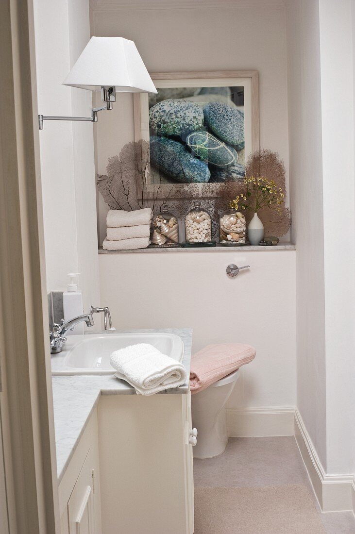 Klassisches Badezimmer mit Marmorwaschtisch und Ablage mit gerahmtem Bild und Muscheldeko