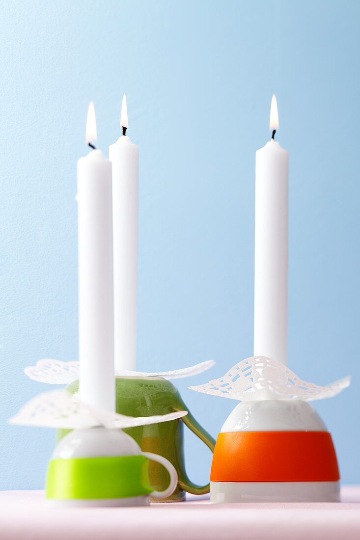 Umgestülpte Tassen als Kerzenständer mit Tortendeckchen als Tropfschutz