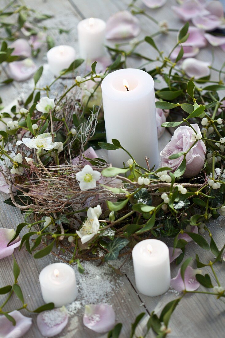 A wreath of pink roses, mistletoe and hellebores with a candle