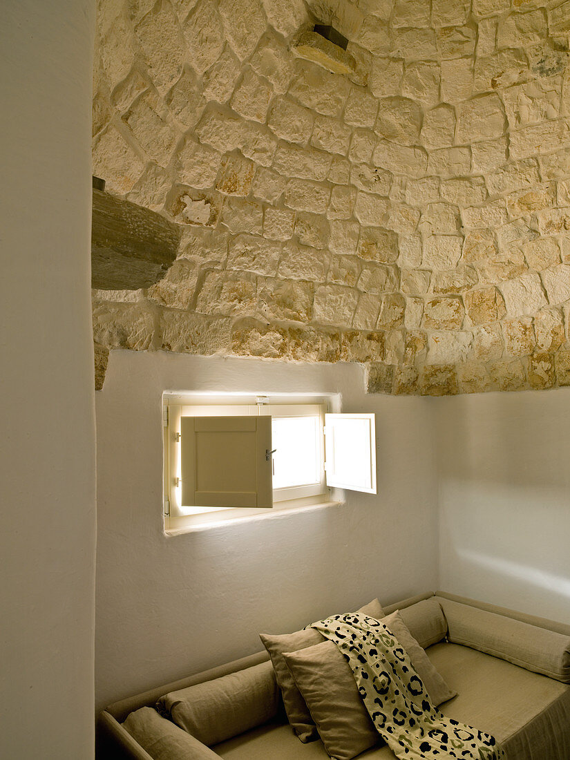 Modern sofa below small window in Trullo house
