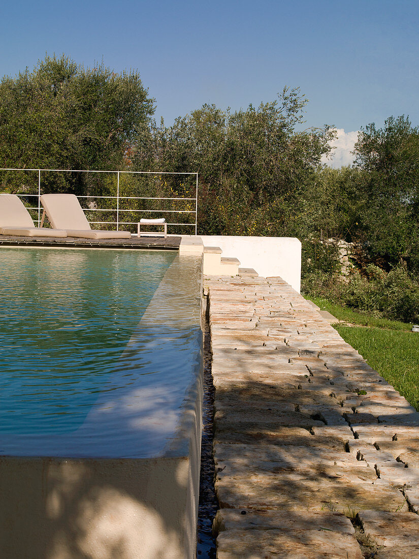 Pool mit Wasserüberlauf und Weg aus Naturstein Quadern in mediterranem Garten