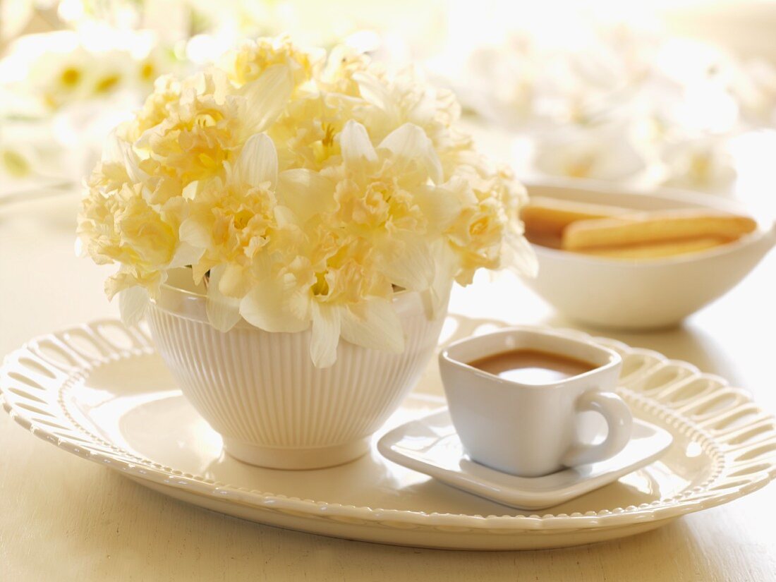 Kaffeetasse und Blumenschale mit Narzissen auf Tablett