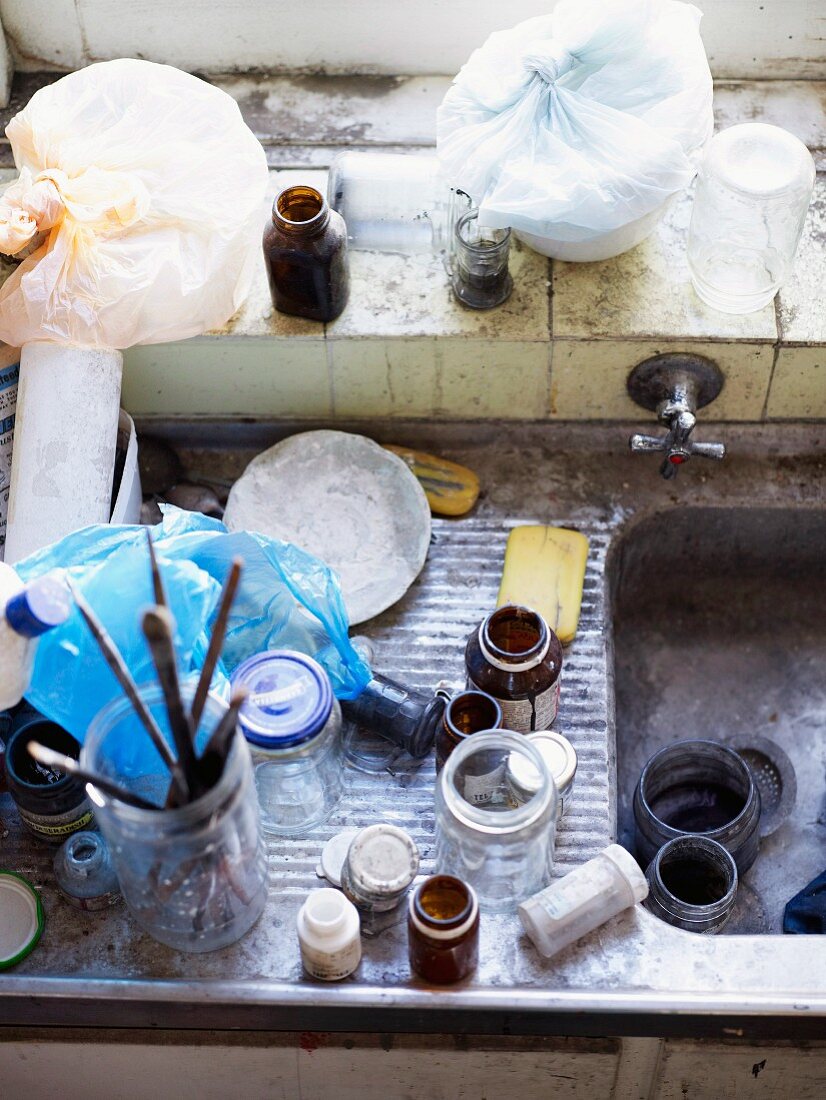 Top view of various jars and paintbrushes in dirty sink