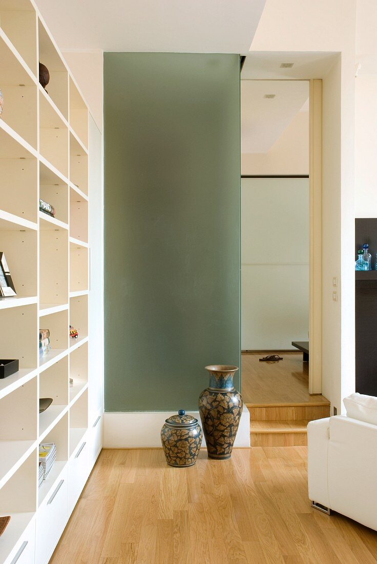 Moderne Wohnzimmerecke - Chinesische Vasen vor Glaswand neben Durchgang und modernes Einbauregal in Weiß